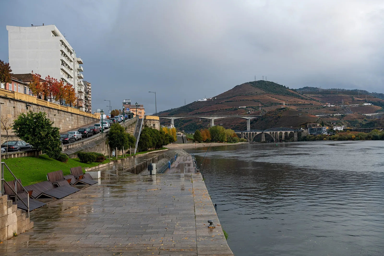 Cais da Régua junto ao rio Douro, com o passeio molhado e a ponte ao fundo